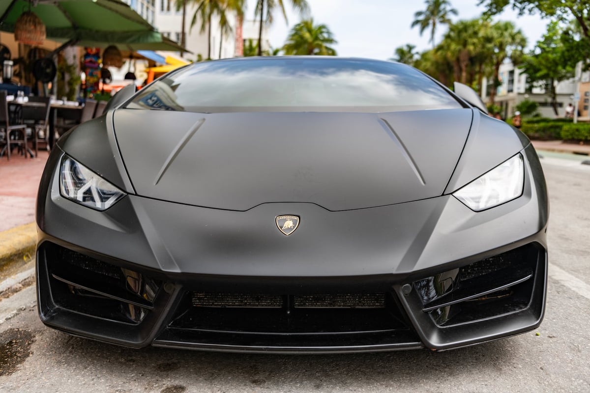 Black matte Lamborghini Huracán front view, aggressive supercar stance with sleek headlights
