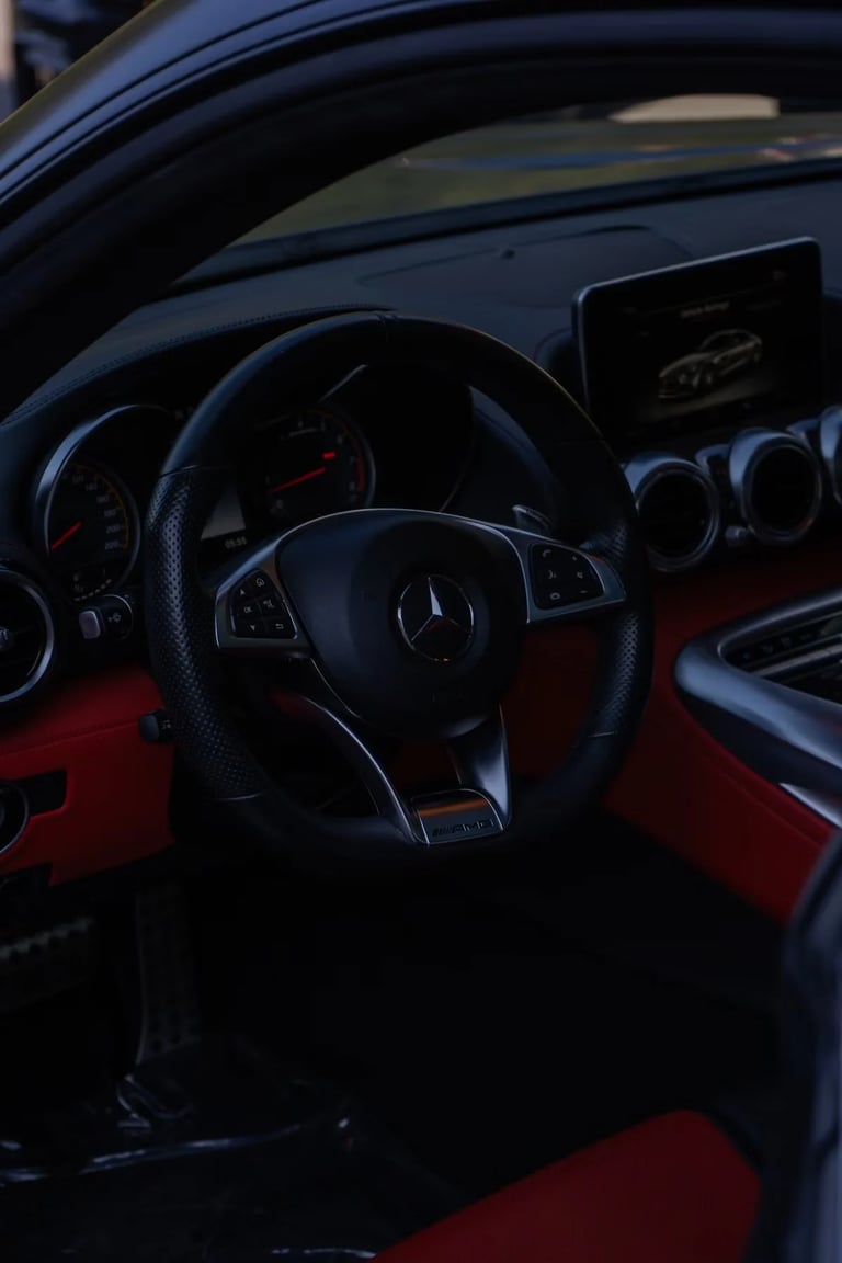 Interior view of a Mercedes-Benz sports car with a black steering wheel, red and black leather seats, and digital dashboard display