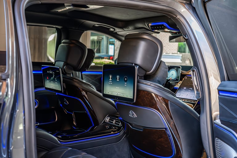 Luxury car interior with blue ambient lighting, dual touchscreen displays, leather seats, and modern dashboard design