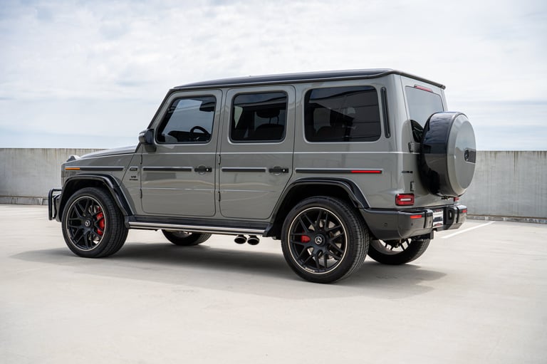 Gray Mercedes-Benz G-Class SUV with custom red brake calipers and spare tire, parked in profile view