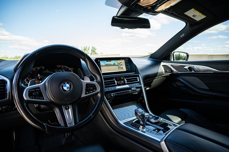 Interior view of a BMW vehicle dashboard with steering wheel, center console, and touchscreen display while driving on a highway