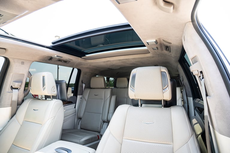 Interior of a spacious SUV with white and gray leather seats, sunroof, and panoramic headliner