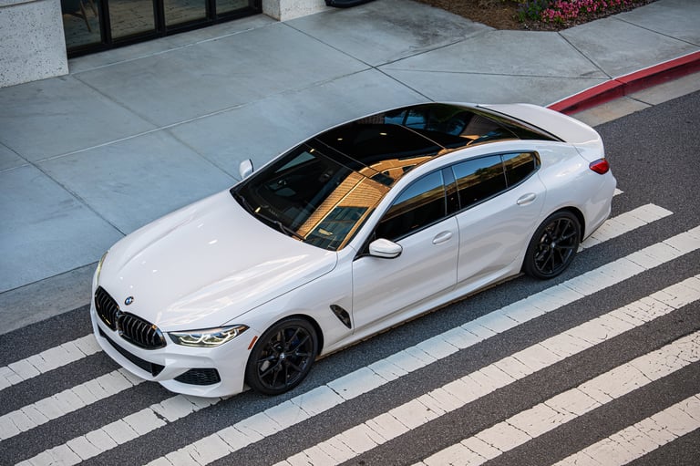 White BMW sedan with tan interior roof parked at pedestrian crosswalk on urban street