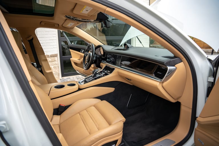 Luxury car interior with tan leather seats, steering wheel, and dashboard visible through open drivers side door