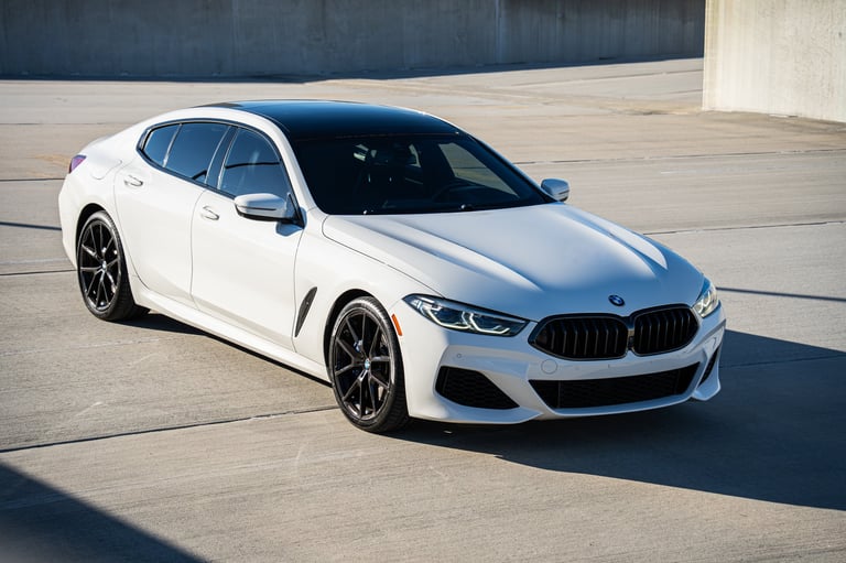White BMW sedan with dark grille parked on concrete surface in daylight