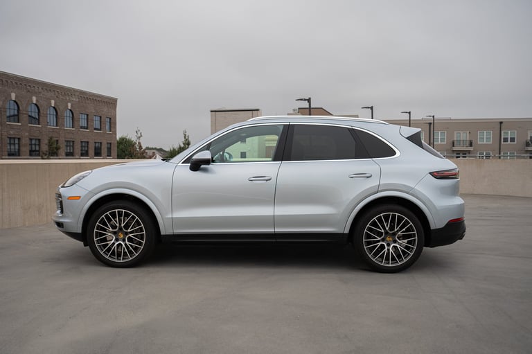 White luxury SUV parked on empty lot with brick buildings in background