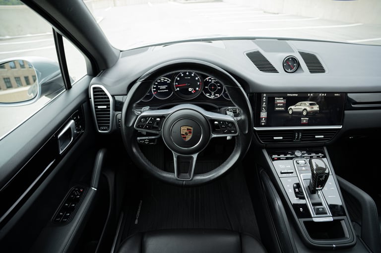 Interior dashboard view of a Porsche sports car with steering wheel, digital display, and modern controls